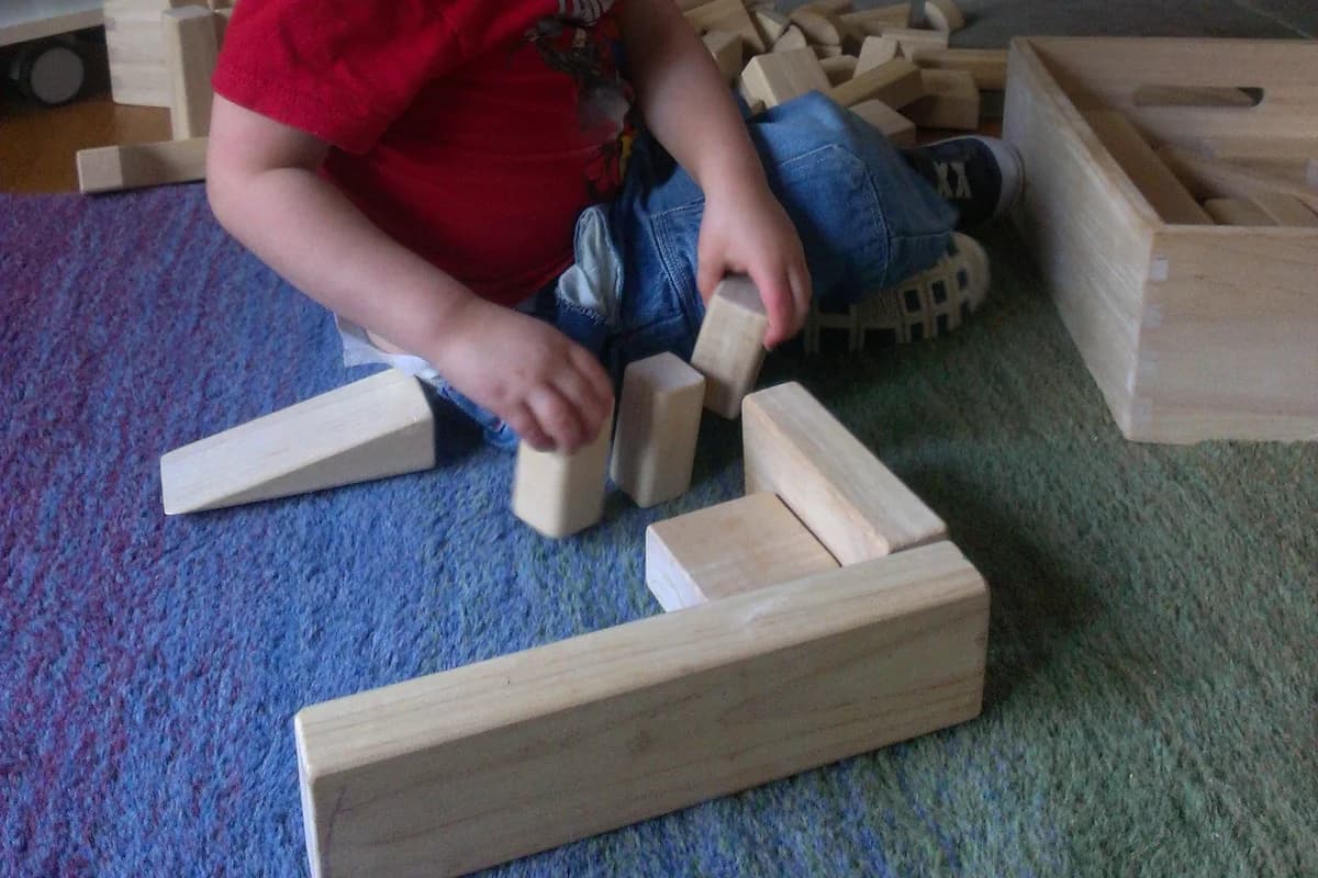 Close-up of a young child carefully balancing wooden unit blocks during deep independent play