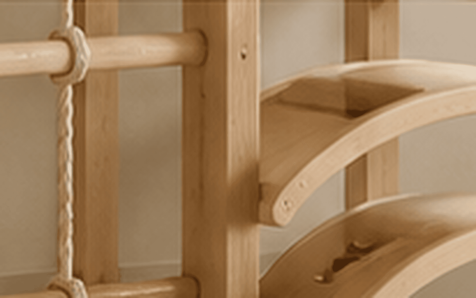 Close-up of natural wood climbing grips, rope ladder and curved balance elements showing crafted play details.